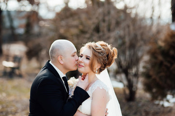 Romantic embrace of newlyweds. Couple walks in the park. Bride and groom kissing in an autumn park. Wedding beautiful loving couple posing. The bride with groom