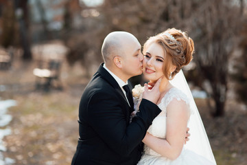 Beautiful couple in love newlyweds. Bride and groom at wedding day walking outdoors. Stylish and beautiful. Bridal couple, newlywed woman and man embracing with love. Wedding day.