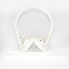 Wireless white headphones on white background. Trendy vintage accessories in creative retro design. Music hipster concept in minimal style.