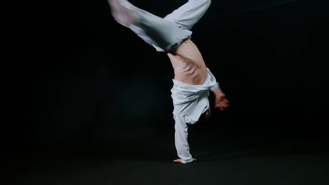 Young man dancer performing break dance trick indoors
