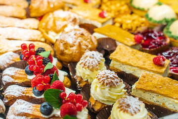 Pastry shop with variety of donuts, muffins, creme brulee, cakes with fruits and berries