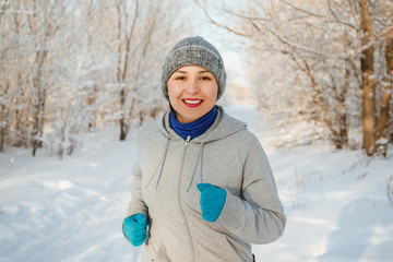 Fototapeta na wymiar Running sport woman. Female runner jogging in cold winter forest wearing warm sporty running clothing and gloves.