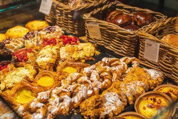 Pastry shop with variety of donuts, muffins, creme brulee, cakes with fruits and berries