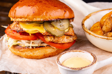 Chicken burger with salts and fresh tomatoes, served with cheese sauce