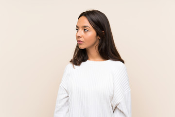 Obraz premium Young brunette woman with white sweater over isolated background looking side