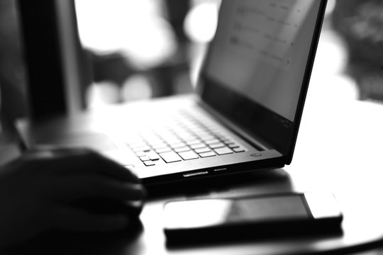 Fototapeta Close up view of laptop and mobile phone with freelancer working on it black and white