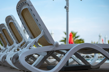 A row of beach chairs by the swimming pool near the hotel. Selective focus.