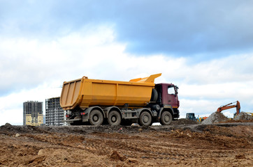 Dump truck transports sand and other materials at construction site. Road repair, construction equipment works, background © MaxSafaniuk