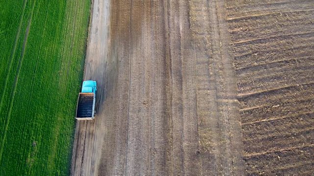 Arial drone footage: Flying above the post soviet era truck riding agricultural feild landscape lit by sunset.