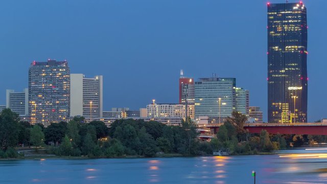 Beautiful cityscape with modern buildings day to night transition timelapse, the tallest skyscraper in Austria reflected in the blue Danube river, in the Donau district of Vienna after sunset.