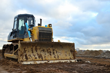 Track-type bulldozer during of large construction jobs at building site. Land clearing, grading, pool excavation, utility trenching, utility trenching and foundation digging. Earth-moving equipment.