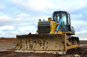 Track-type bulldozer during of large construction jobs at building site. Land clearing, grading, pool excavation, utility trenching, utility trenching and foundation digging. Earth-moving equipment.