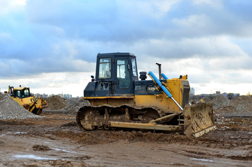 Track-type bulldozer during of large construction jobs at building site. Land clearing, grading, pool excavation, utility trenching, utility trenching and foundation digging. Earth-moving equipment.