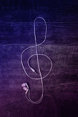 Headphones from a smartphone. Treble clef. Lies on a wooden background. The concept of love for music. Neon light