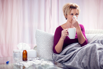 Woman got the flu, blowing nose into napkin. People, healthcare and medicine concept