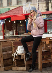 Portrait of a young beautiful happy woman with candy posing on the street of a European city. Xmas.