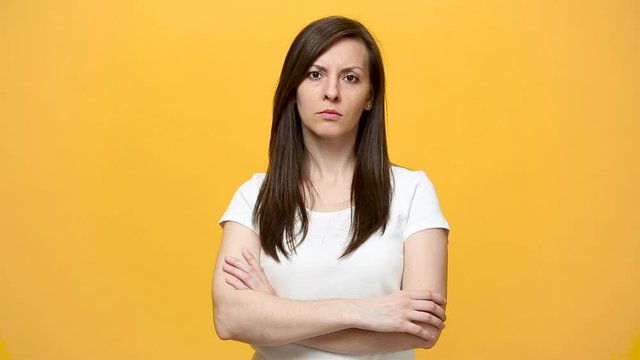 Perplexed confused thinkful pensive brunette young woman in white t-shirt looking camera gesticulating say what isolated over yellow background in studio. People sincere emotions, lifestyle concept.