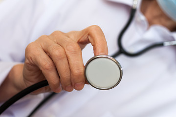 Close up hand female doctor in blue medical mask showing stethoscope for checkup auscultate...