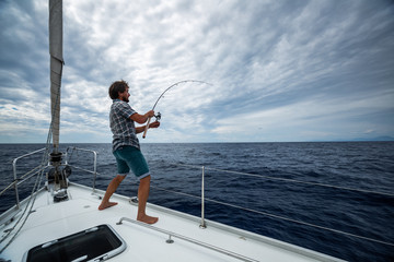 Young man fishing from the sail boat