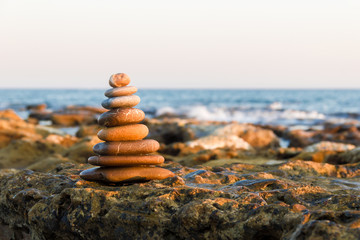 Stack of stones against blurred seascape, space for text. Zen concept.