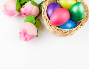 Fototapeta na wymiar happy Easter, colored eggs in a basket and spring flowers on a white background, spring Orthodox Christian and Catholic holiday, banner with space for text