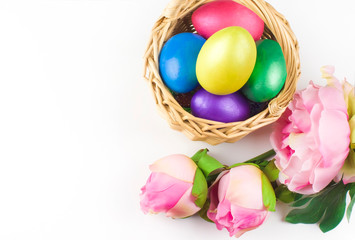 Obraz na płótnie Canvas happy Easter, colored eggs in a basket and spring flowers on a white background, spring Orthodox Christian and Catholic holiday, banner with space for text
