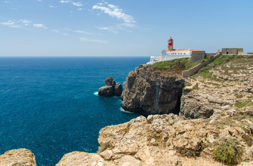 Fototapeta na wymiar Portugal, Algarve, view of cliffs of Moher and Atlantic Ocean, white red lighthouse, lighthouse near Sagres in Portugal, Cape St. Vincent on a sunny day with The blue Atlantic in the background