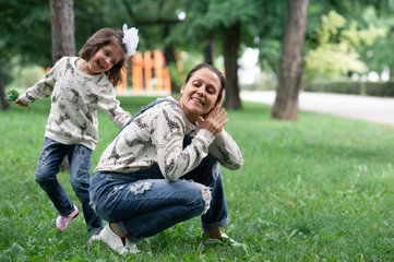Naklejka na ściany i meble daughter with mom play in the park, lively emotions laugh and have fun. That when people are happy.