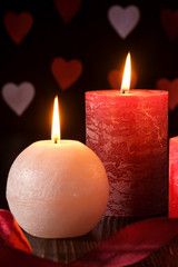 Three wax flame candlelight with ribbon in dark romantic light on hearts background, love dating, Valentine's day, selective focus