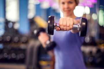 Woman training with dumbbells in the gym. People, fitness and health concept