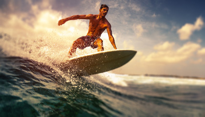 Surfer rides ocean wave in tropics. Tilt shift effect applied