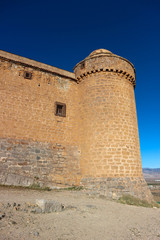 Fototapeta na wymiar Towers of medieval spanish castle La Calahorra on the hill against azure winter sky