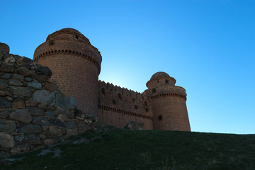 Fototapeta na wymiar towers of the medieval spanish castle La Calahorra behind the outer wall in the light of the evening sun, Granada, Spain