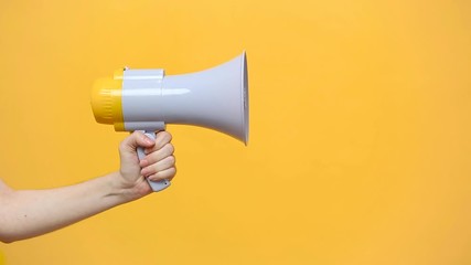 Close up female hold in hand bullhorn public address megaphone isolated on yellow background. Hot news, announce discounts sale, hurry up, communication concept. Copy space. Advertising area, mock up.