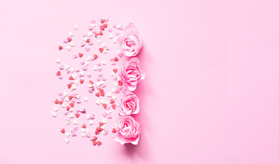 Valentines Day. Heart shape formed of sweet confetti on pink background with rose flower. Template mock up of greeting card or text design