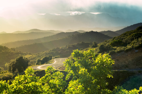 A landscape with a road going through foggy mountains, Corbieres, France