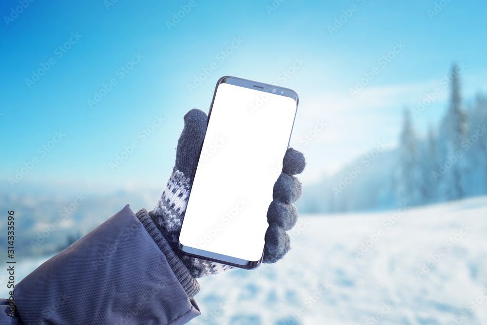 Poster phone in hand with glove. concept of using mobile phone in winter, cold time. isolated screen for mo