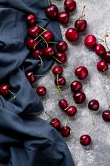 Ripe cherry berries on a gray fabric and on a concrete background