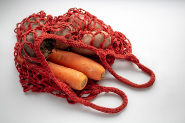 Trendy net shopping bag with potatoes on white background. Ugly, unnormal vegetable, zero waste and plastic free concept. Copy space.