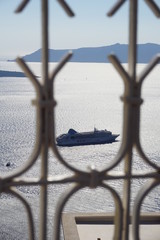 Cruise ship passing by the mountain side of Santorini, Greece in the open ocean