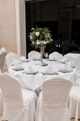 White table serving with white chairs and a floral centerpiece