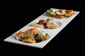 Assortment of various canapes on white plate.