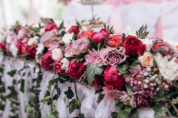 Floral composition on the wedding table made of pink roses and peonies