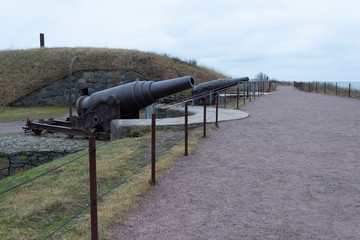 Old cast-iron artillery Russian guns, old granite fortifications of the island-fort Suomenlinna overgrown with grass, Suomenlinna, gloomy autumn day in Finland.