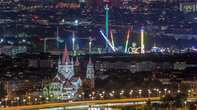 Aerial panoramic view over Vienna city with Church of St. Francis of Assisi, prater and a riverside promenade night timelapse in Austria. Illuminated skyline from Danube Tower viewpoint