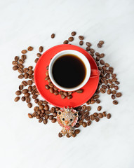 red cup of black coffee, coffee bean and cute jewelry lion brooch on light background. Luxurious gold jewelry in form of a lion. minimal composition, copy space. top view. template for design