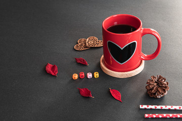 Red sweet heart coffee cup, colorful LOVE cube boxes, decor wood hearts, pieces of flower, pine cone, heart straws on black background with nature sunlight