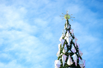 Christmas tree on a background of blue sky with clouds. The main city Christmas tree in the square.
