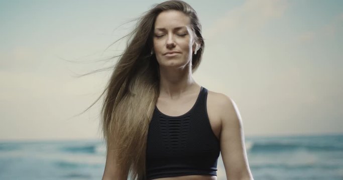 caucasian brunette middle aged woman meditating at the beach. Sea in the blurred out background. 4k, slow motion, handheld. 
