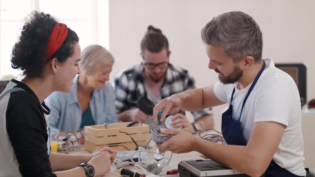 A group of people at repair cafe repairing household electrical devices.